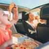 father and daughter eating pizza in the car