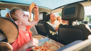 father and daughter eating pizza in the car