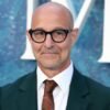 Stanley Tucci smiles in glasses and suit