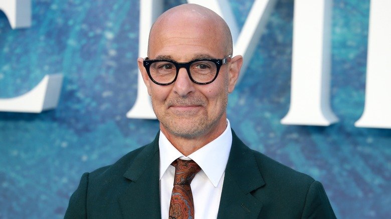 Stanley Tucci smiles in glasses and suit